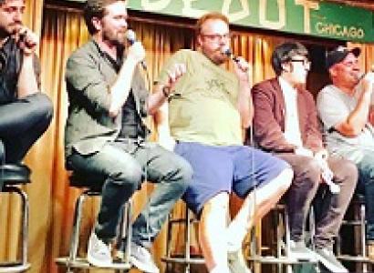 Different sizes and types of white guys sitting on stools on a stage, a couple talking into mics