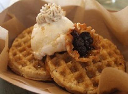 Two brown waffle-ish looking foods on a plate with a dollup of something white and something purple