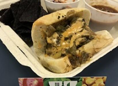 Sandwich in a carton with two bowls of food and a card in front that says Can't Believe It's Vegan