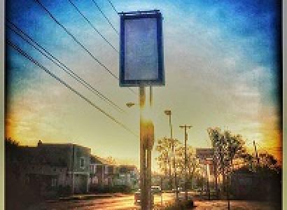 Blue background sky with a tall rectangular sign that is blank on a city street