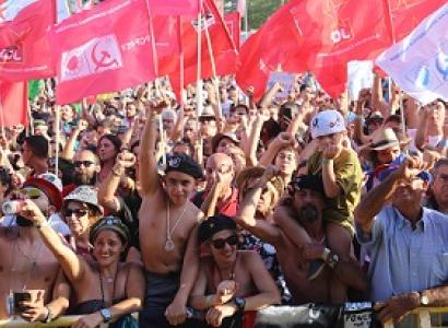 Hundreds of people outside waving lots of red flags