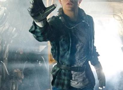 Man with big screen-like goggles like virtual reality headgear with a big glove stretched out on his hand 