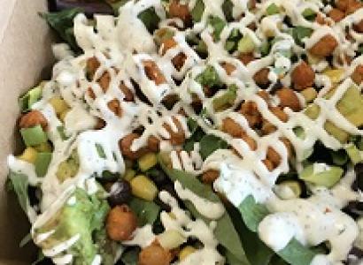 A round pizza looking piece of food that looks like beans and crisscross dribbles of white cream