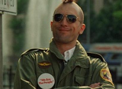 Robert De Niro, youngish white man with a mohawk hairsut and sunglasses smiling with his arms crossed, wearing an army jacket with patches