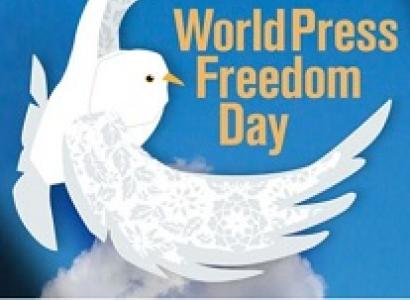 Bright blue background and drawing of white dove with wings encircling the words World Press Freedom Day