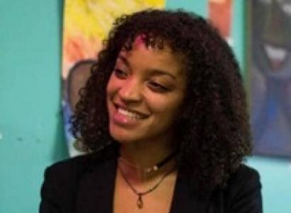 Young black woman smiling in a black suit against a colorful background