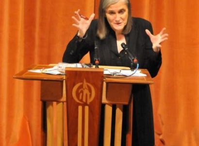 Amy gesturing with both hands at a podium