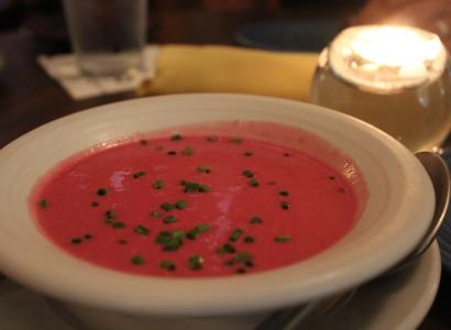 White bowl with red soup and green chives sprinkled on top