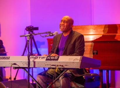 Bald black man singing at a keyboard
