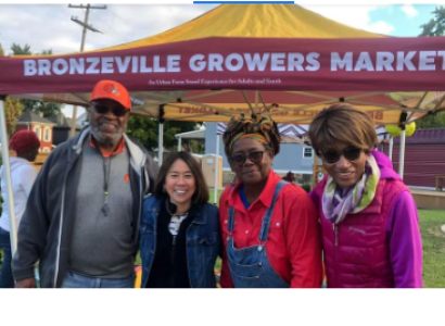 People posing in front of a Bronzeville Growers Market sign