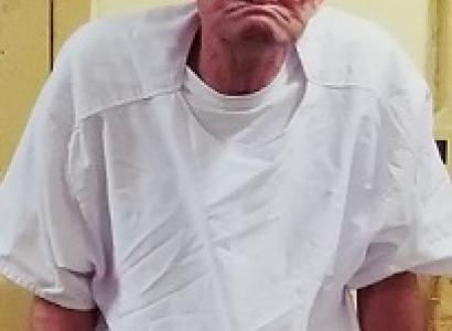Bald old man with black-rimmed glasses and ears sticking out on each side of his had big a huge frown as if he has not teeth in a white hospital gown looking very sad