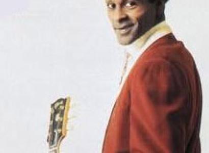 Black man in red suit holding a guitar