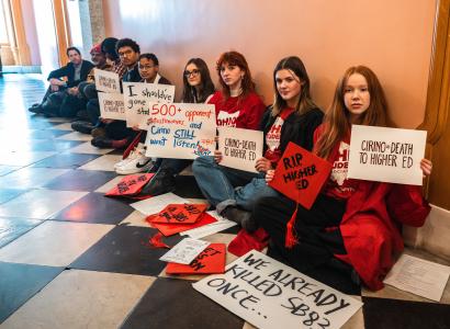 Students with protest signs sitting in a hall