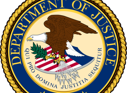 Round official seal with gold braided outside rim and blue around the circle that has words Department of Justice and an eagle facing left with wings held high on top of a shield with flag colors red, white and blue, 