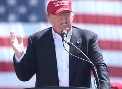 Trump in front of flag with red baseball cap on