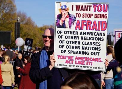 Man outside holding a sign about what Americans fear