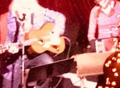 Two guys on stage one playing guitar