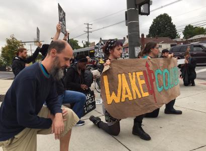 Protesters with signs down on one knee