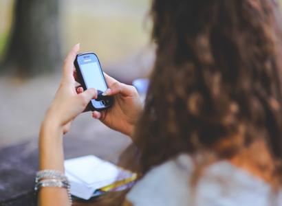 Side view of girl with brown curly hair looking at cellphone