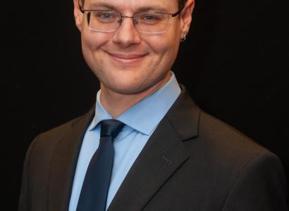 White man in a suit and glasses smiling
