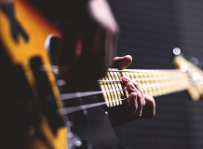 Sideways shot of a person playing a guitar close up of just the guitar and their hands