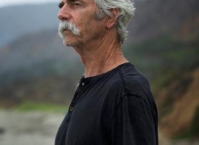 white haired man with moustache standing outside hair blowing in wind
