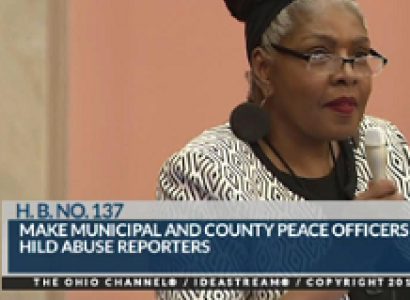 Black woman in glasses with hair rolled up on top of head with pink background and words at the bottom 