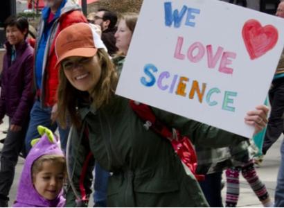 Woman with child and sign saying We Love Science