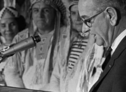 Lyndon Johnson at a mic and Native men in background