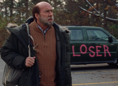 Man with backpack by a car with painting on it saying LOSER