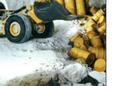 Bulldozer pushing yellow barrels into a ditch