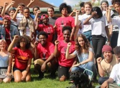 Young people posing outside wearing mostly red shirts with their fists in the air
