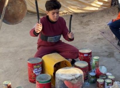 Young boy playing on homemade drums