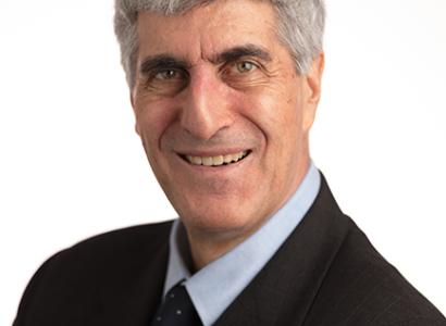 Head shot of gray haired smiling man in dark suit