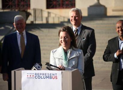 Woman speaking at podium outside at press conference