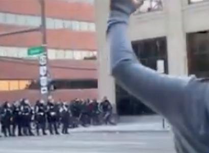 Police line and demonstrator with hands in air