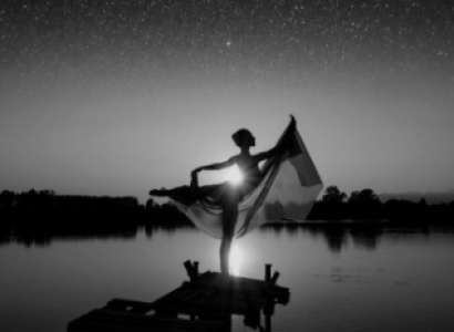 Silhouetted figure of woman posing near a lake and horizon 