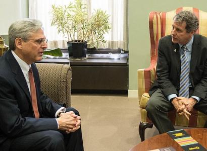 Merrick Garland and Sherrod Brown sitting in chairs looking at each other