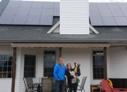 Solar panels on home with man, woman and child out front
