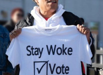 Woman holding T-shirt saying Stay Woke Vote