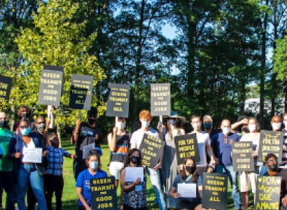 People posing outside by trees with signs