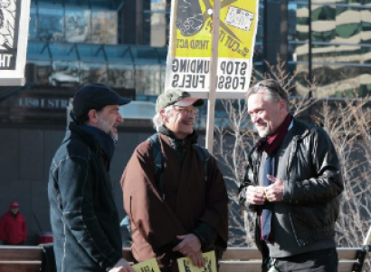 Three men talking outside at a protest