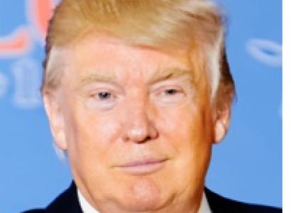 Old white man with orange hair coming down on his forehead looking goofy