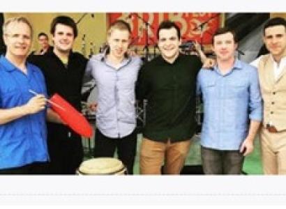 Six white men posing in a line with musical instruments