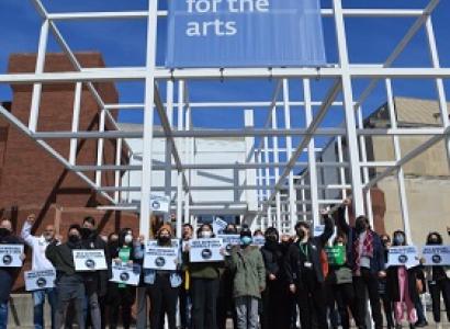 Workers holding signs under the Wexner Center for the Arts sign on building