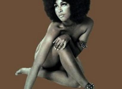 Sixties-looking photo of naked black woman covering up her private parts with arms and legs, she has a huge Afro against a brown background