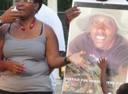 Black woman talking and pointing to photo of her son, young black man