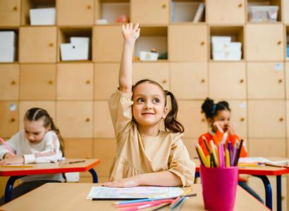 GIrl in classroom raising hand