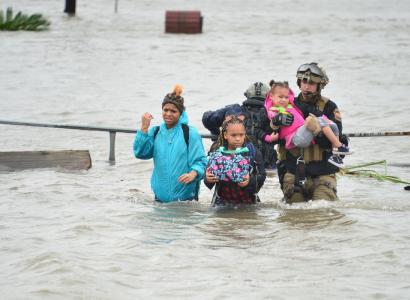 People wading through wasit deep flood