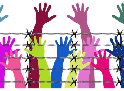 Different color arms and hands reaching up behind a barbed wire fence